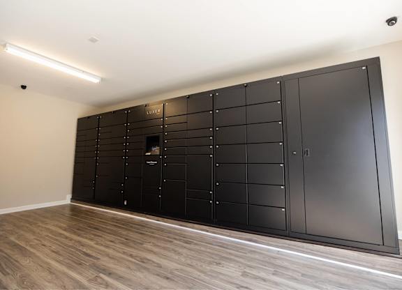A large black wardrobe with a mirror on the front is in a room with wooden flooring.