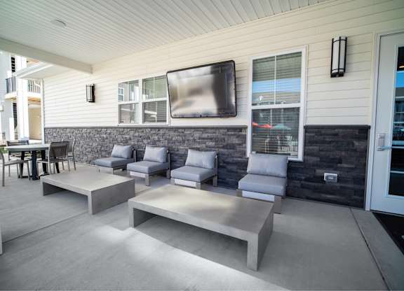 A patio with grey furniture and a flat screen TV mounted on the wall.
