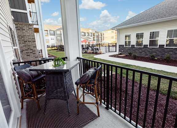 A patio with a table and chairs overlooking a grassy area.
