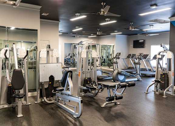 A gym with a variety of equipment including treadmills, weights, and exercise machines.