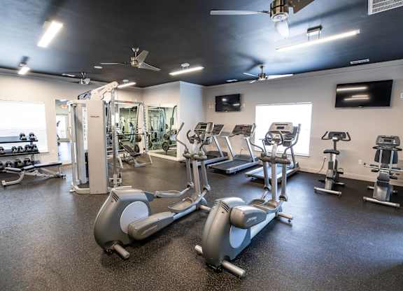 A gym with a row of treadmills and elliptical machines.