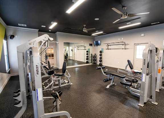 A gym with a variety of equipment including a weight bench, a squat rack, and a barbell.