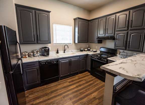 A kitchen with black cabinets and a wooden floor.