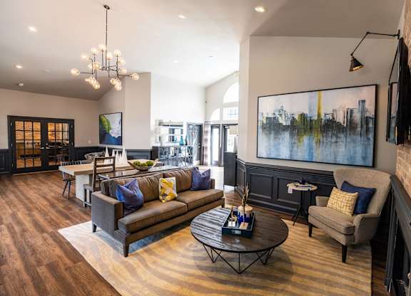 A living room with a brown couch and a painting on the wall.