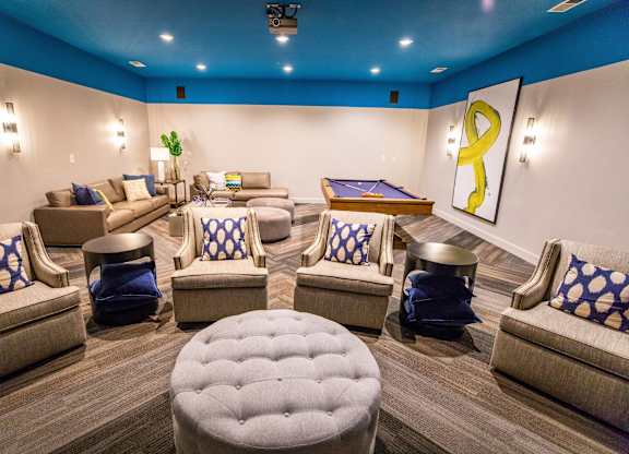 A room with a pool table and comfortable seating.