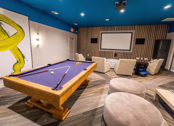 A pool table is in the middle of a room with a blue ceiling.