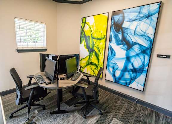 A room with a table, chairs and two computer monitors.