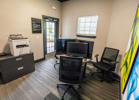 A room with a printer, two chairs, and a TV.
