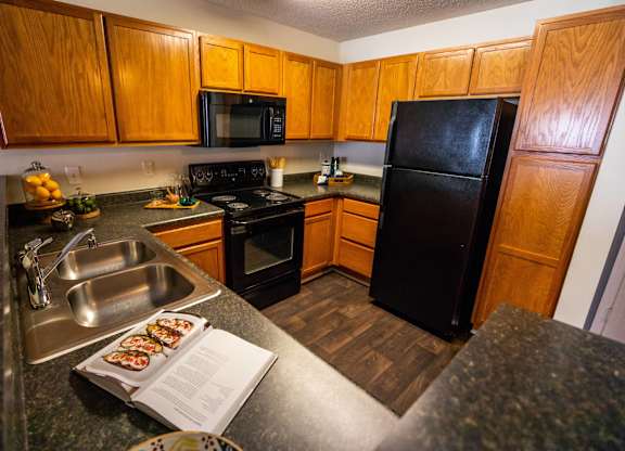A kitchen with wooden cabinets and a black refrigerator.