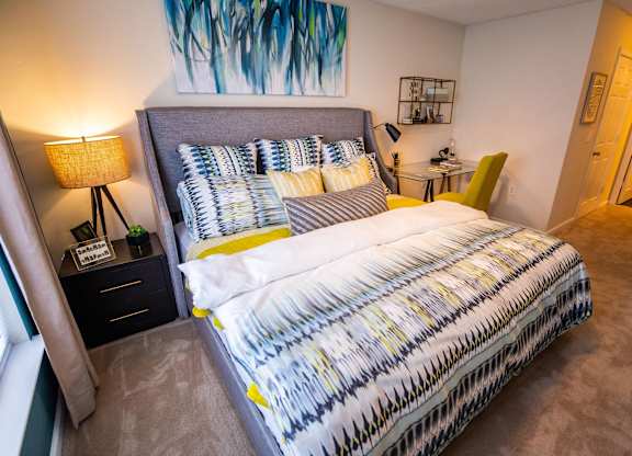 A bed with a white and yellow comforter and a grey headboard.
