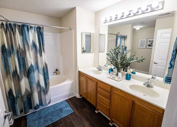 A bathroom with a blue rug and a shower curtain with blue and white patterns.