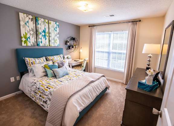 A bedroom with a large bed and a window with curtains.