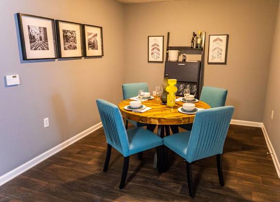 A dining table with four chairs and a shelf with decorative items.