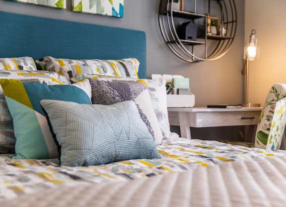 A bed with a blue headboard and a white bedspread with yellow and blue pillows.