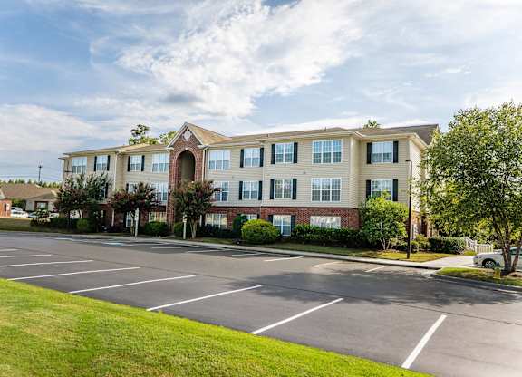 A large apartment building with a parking lot in front.