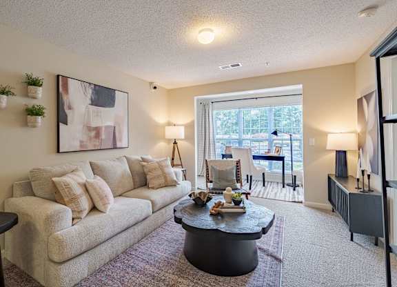 A living room with a couch, a coffee table, and a painting on the wall.