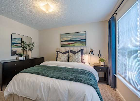 A bedroom with a large bed and a painting on the wall.