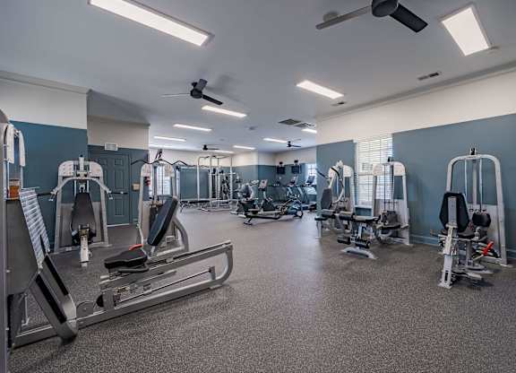 A spacious gym with a variety of equipment including treadmills, weight machines, and a rowing machine.