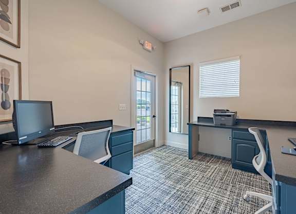 A room with a desk and chairs with a computer on it.