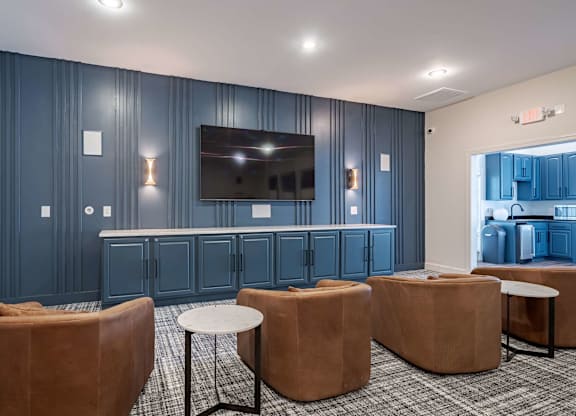 A room with a television, chairs, and a table.