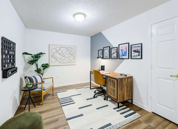 A room with a desk, chair, and pictures on the wall.
