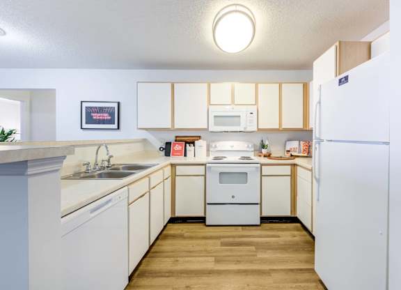 A kitchen with white cabinets and a white fridge.