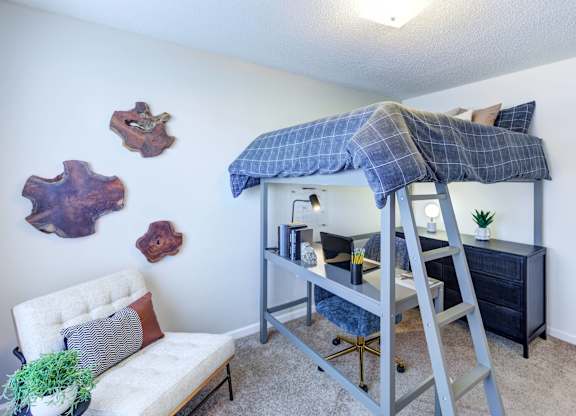 A room with a bunk bed and a white chair.
