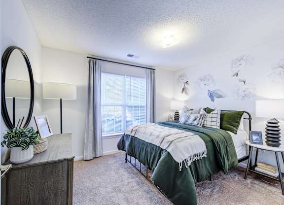 A bedroom with a bed, a dresser, and a mirror.
