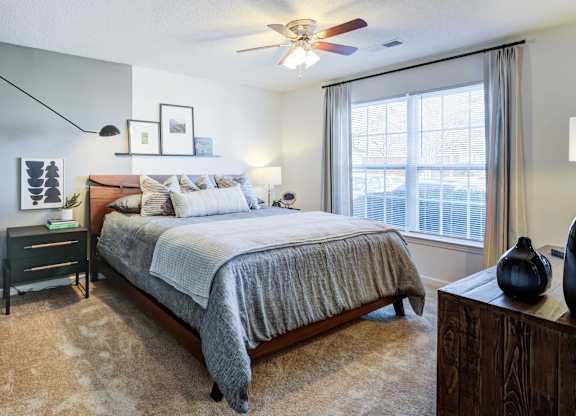 A bedroom with a large bed and a ceiling fan.
