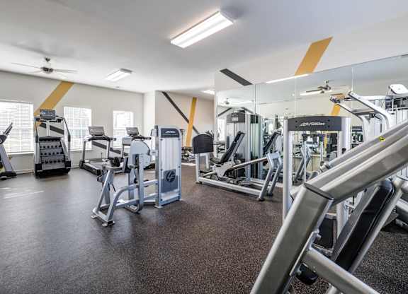 A gym with a variety of equipment including treadmills, weights, and exercise machines.