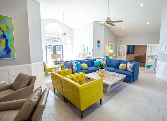 A living room with a yellow ottoman and blue couches.