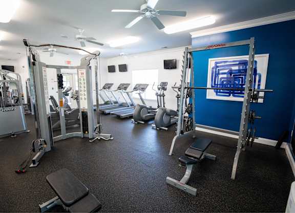 A gym with a variety of equipment including weights and a treadmill.