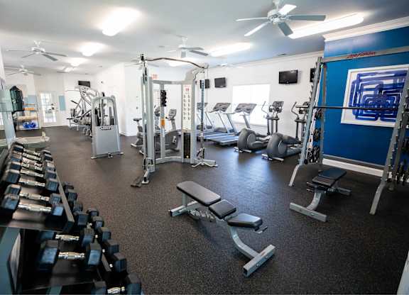 A gym with a variety of equipment including treadmills, weights, and exercise machines.