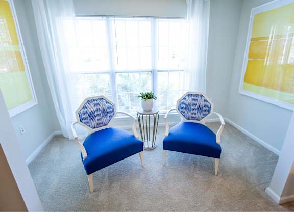Two blue chairs facing a window in a room.