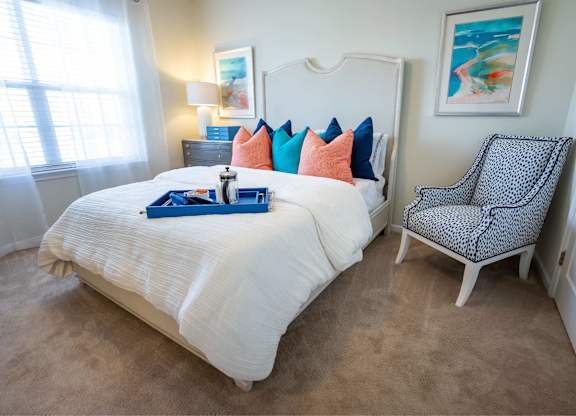A bedroom with a white bed and a chair with a black and white pattern.