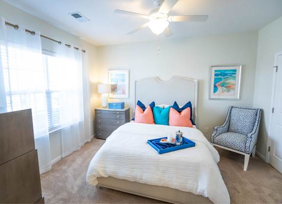 A bedroom with a bed, chair, and a ceiling fan.