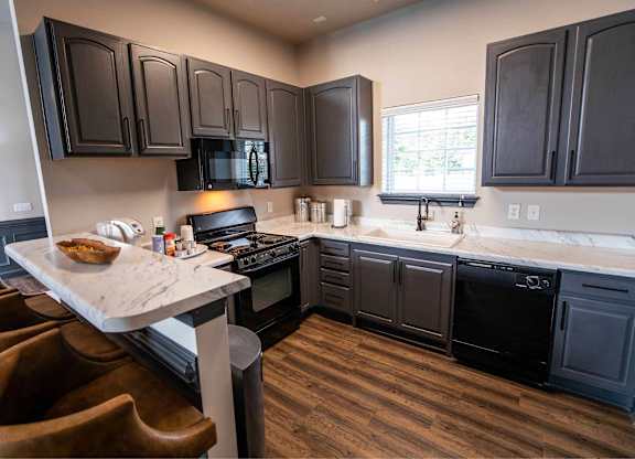 A kitchen with dark wood cabinets and a marble island.