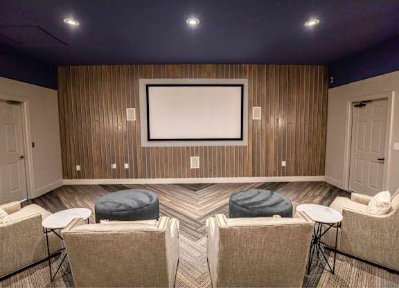 A room with a large screen and comfortable seating.