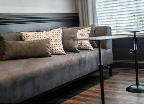 A grey couch with four pillows on it.