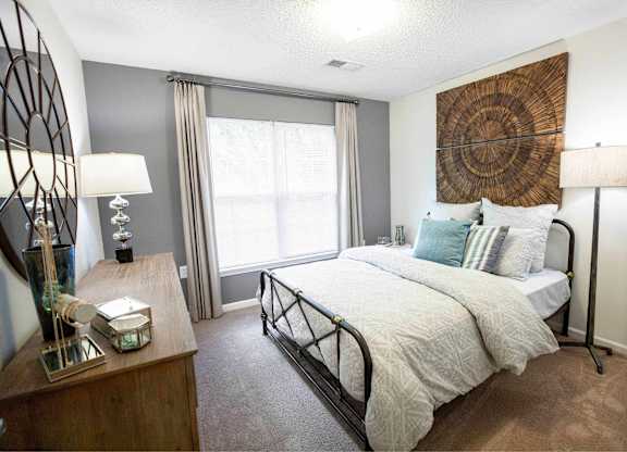 A bedroom with a large bed and a wooden dresser.