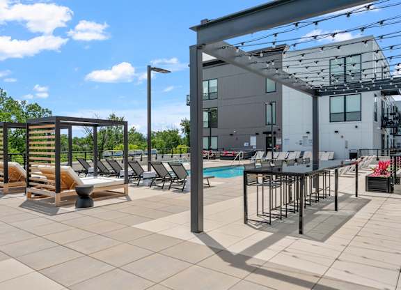 A pool area with a sun lounger and a building in the background.