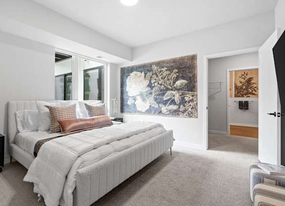 A bedroom with a large bed and a painting on the wall.