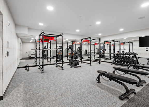 A gym with a variety of equipment including treadmills, weights, and exercise machines.