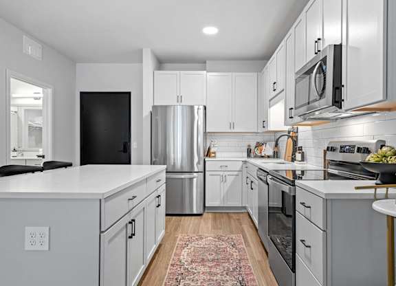 A modern kitchen with stainless steel appliances and white cabinets.