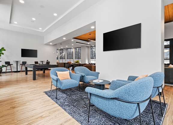 A modern living room with blue chairs and a flat screen TV mounted on the wall.