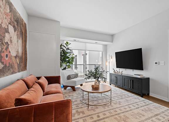A living room with a brown sofa and a large painting on the wall.