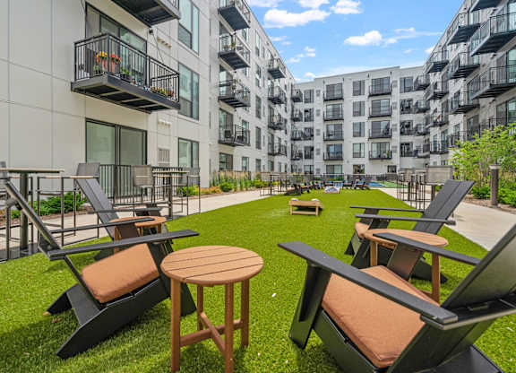 A patio with chairs and tables is surrounded by apartment buildings.