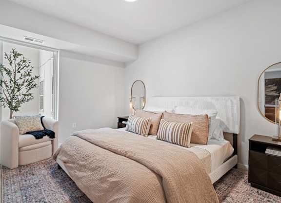 A bedroom with a large bed and a chair.