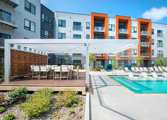 A modern apartment complex with a pool and outdoor seating area.