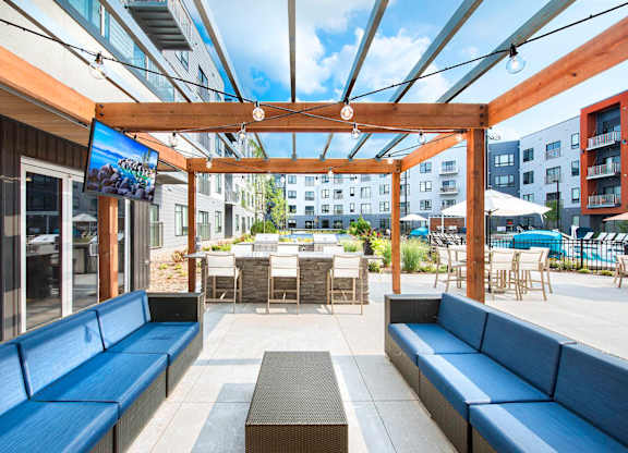 A patio with blue couches and a TV screen.